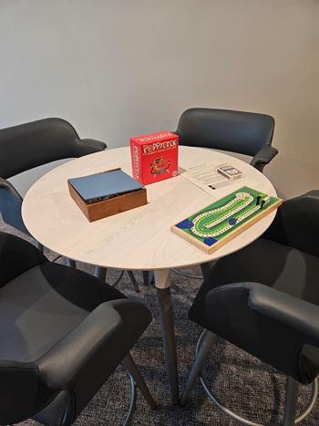 A round table with a book and a box on it surrounded by chairs.